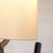 Close-up of a textured lampshade on a handmade wooden floor lamp, showcasing its unique design and craftsmanship.