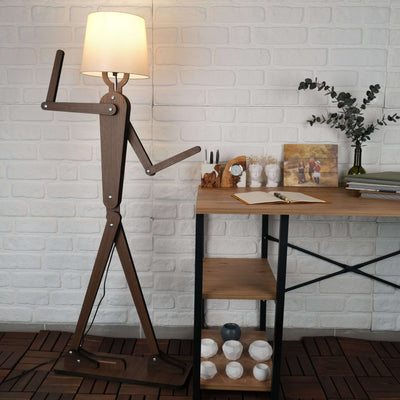 Handmade wooden floor lamp with original design beside a modern desk and decorative items in a stylish interior setting.